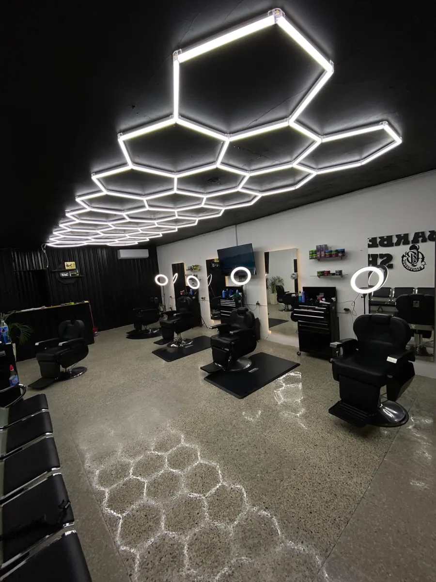 Interior de GB Barbería con sillones negros y luces geométricas